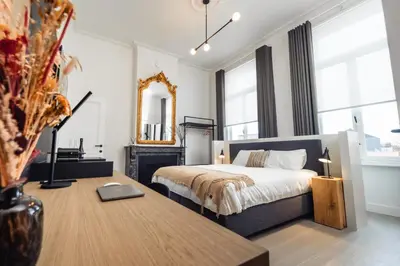 a bedroom with a bed and a table and a mirror at Luxeverblijf B&B het Wevershuis in Herentals