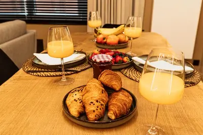 a table with plates of food and glasses of orange juice at Golden Dove Luxury Apartment in Brussels