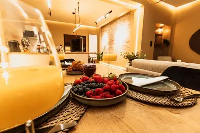a table with a bowl of fruit and a glass of juice at Golden Dove Luxury Apartment in Brussels