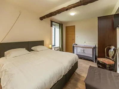 a bedroom with a large white bed and a chair at Glabbeek Family Retreat Home in Bunsbeek