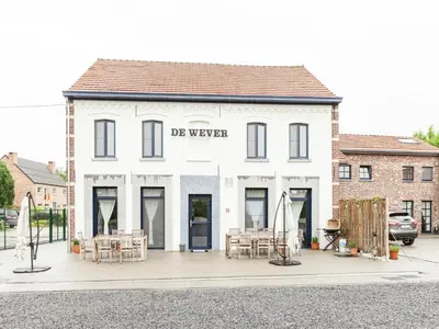 a white building with tables and chairs in front of it at Glabbeek Family Retreat Home in Bunsbeek