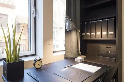 an office with a desk with a clock and a window at Getaway Leuven in Leuven