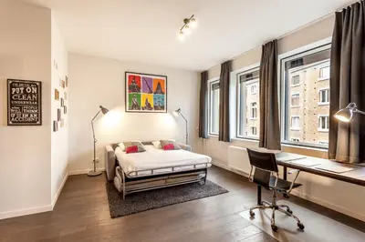 a bedroom with a bed and a desk and windows at Getaway Leuven in Leuven