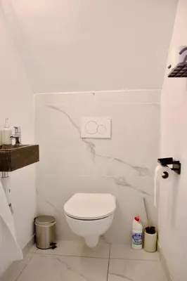 a white bathroom with a toilet and a sink at Chez Nadège in Affligem