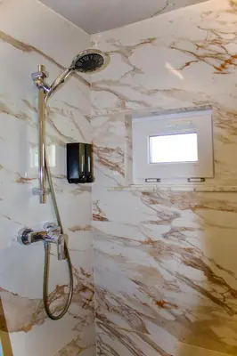 a shower in a bathroom with a marble wall at Chez Nadège in Affligem