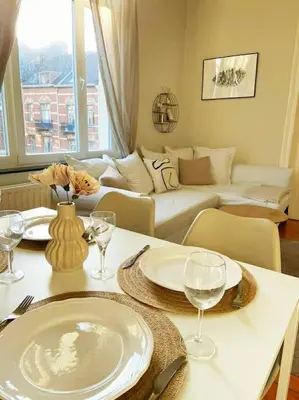 a living room with a table with plates and wine glasses at Cute central flat in Brussels in Brussels