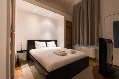 a bedroom with a bed and a flat screen tv at The American Loft in Brussels