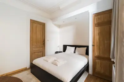 a bedroom with a bed with white sheets and wooden doors at The American Loft in Brussels