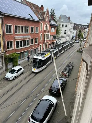 a bus driving down a street with parked cars at Ces Home Centrum in Ghent
