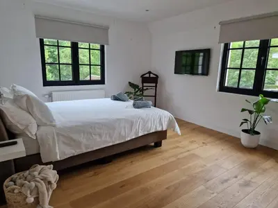 a bedroom with a bed with white sheets and windows at Villa Tibur - Near Boom & Rumst in Rumst