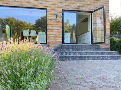 a house with a glass door and some purple flowers at Villa Tibur - Near Boom & Rumst in Rumst