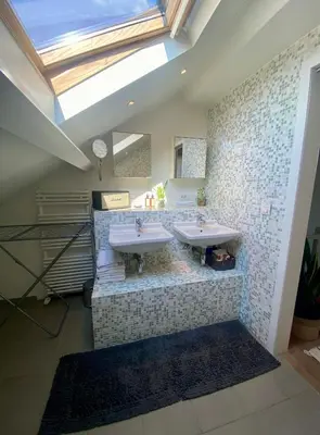 a bathroom with two sinks and a skylight at Stijlvolle duplex nabij Brussel en luchthaven! in Meise