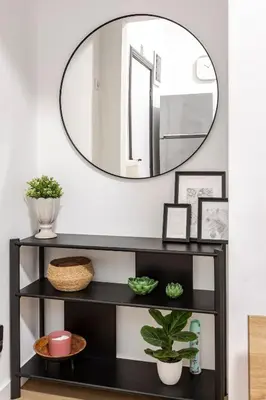 a black shelf with a round mirror on a wall at Cosy Appartement met Tuin in Centrum Antwerpen - Gratis Parking & WiFi in Antwerp