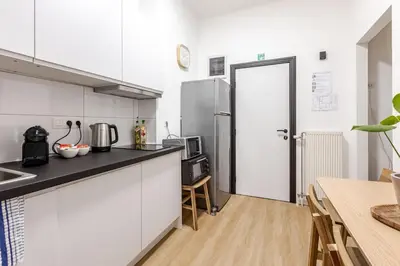 a kitchen with white cabinets and a refrigerator and a table at Cosy Appartement met Tuin in Centrum Antwerpen - Gratis Parking & WiFi in Antwerp