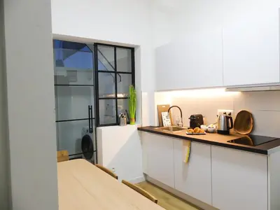 a kitchen with white cabinets and a counter top at Cosy Appartement met Tuin in Centrum Antwerpen - Gratis Parking & WiFi in Antwerp