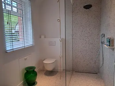 a bathroom with a toilet and a glass shower at Het Bed van den Doktoor in Meerhout