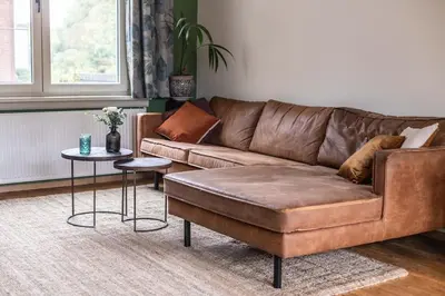 a brown leather couch in a living room with a table at Gezellig appartement op het hippe Zuid in Antwerp