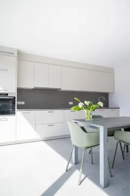 a kitchen with white cabinets and a table and chairs at Green HOME Wieze in Wieze