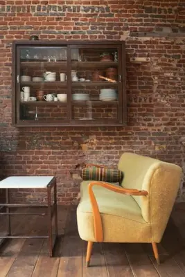 a living room with a chair and a brick wall at Het Bosnest, een vakantiewoning aan het Hallerbos in Halle