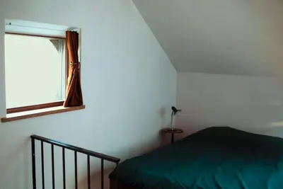 a bedroom with a green bed and a window at Het Bosnest, een vakantiewoning aan het Hallerbos in Halle