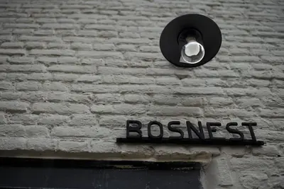 a sign on the side of a brick wall with a light at Het Bosnest, een vakantiewoning aan het Hallerbos in Halle