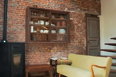 a living room with a brick wall and a couch at Het Bosnest, een vakantiewoning aan het Hallerbos in Halle