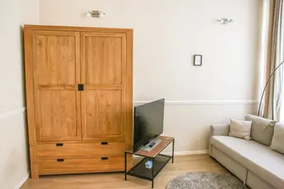 a living room with a couch and a wooden cabinet at Appartement hôtel BRUXELLES CENTRE in Brussels