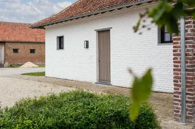 a white building with a door on the side of it at Cuypershof in Oosterzele