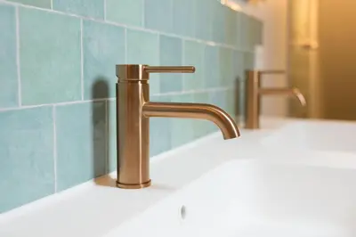 a bathroom sink with a brass faucet in front of a mirror at Cuypershof in Oosterzele