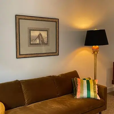 a brown couch in a living room with a lamp at The Cottage in Merelbeke