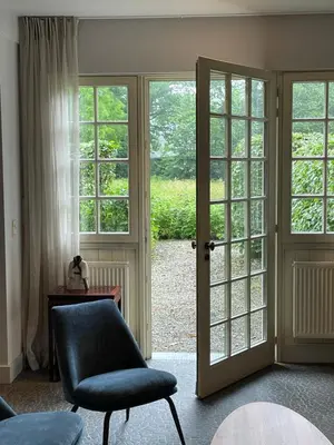 a living room with a chair and a sliding glass door at The Cottage in Merelbeke