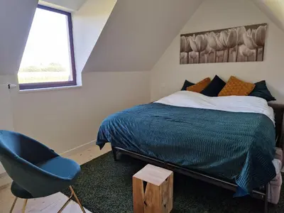 a bedroom with a bed and a blue chair at De Mispel in Groot Schaddeken Dries