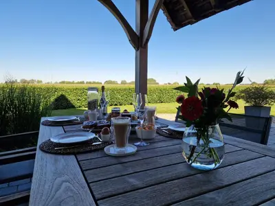 a wooden table with a vase of flowers on it at De Mispel in Groot Schaddeken Dries