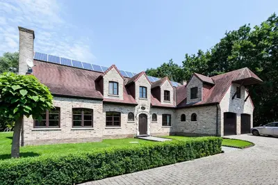 a large brick house with a car parked in front of it at Zenitude in Tremelo