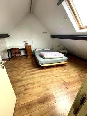 a bedroom with a bed and a wooden floor at Duplex 3 chambres à Saint-Gilles in Brussels