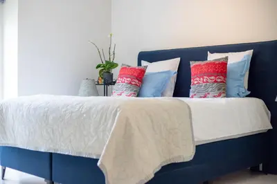 a blue bed with colorful pillows on it at Country Villa - Tervuren in Tervuren