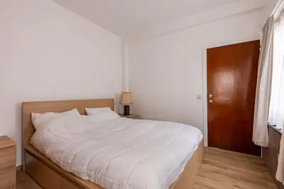a bedroom with a white bed and a wooden door at Antwerp Home Sweet Home 1 Double and 2 Single Beds in Antwerp