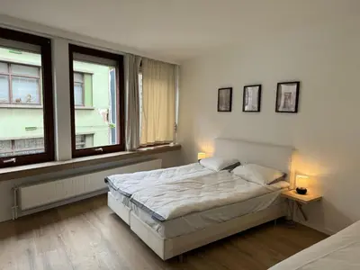 a white bedroom with a bed and two windows at Loft with big terrace city center MEIR in Antwerp