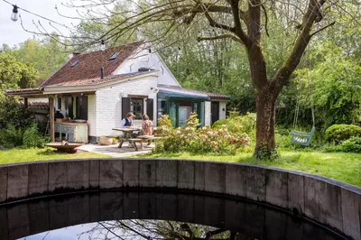a house with a bridge in front of it at La Petite Foret Cottage in Brussels Countryside in Asse