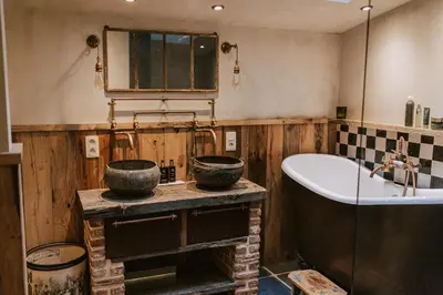 a bathroom with a bath tub and a sink at La Petite Foret Cottage in Brussels Countryside in Asse