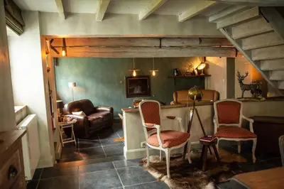 a living room with a couch and a table and chairs at La Petite Foret Cottage in Brussels Countryside in Asse