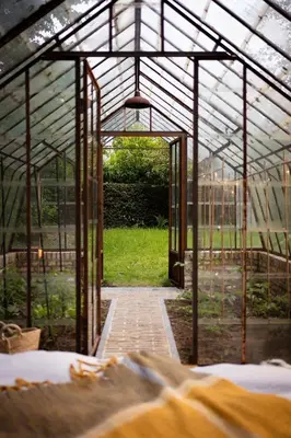 an open glass greenhouse with a walkway in it at La Petite Foret Cottage in Brussels Countryside in Asse
