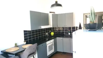 a kitchen with white cabinets and a black tiled wall at ailes Center 1 in Brussels