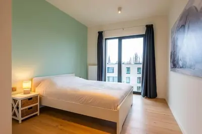 a bedroom with a bed and a large window at Casa Matti - Modern Apartment with Canal View and Terrace in Ghent