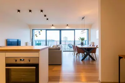 a kitchen and living room with a table and a couch at Casa Matti - Modern Apartment with Canal View and Terrace in Ghent