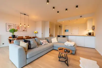 a living room with a blue couch and a kitchen at Casa Matti - Modern Apartment with Canal View and Terrace in Ghent