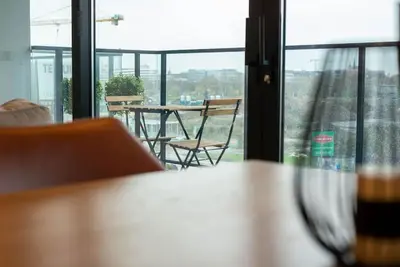 a table and chairs in a room with a window at Casa Matti - Modern Apartment with Canal View and Terrace in Ghent