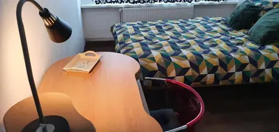 a table with a book on it next to a bed at Lovely room in Mortsel