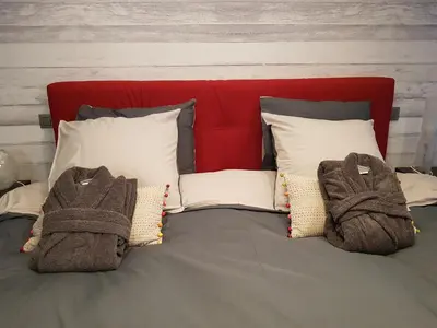 a bed with a red head board with towels on it at B&B De Vlierbeek in Sint-Niklaas