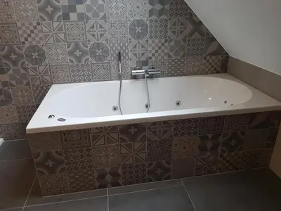 a white bath tub in a bathroom with tiles at B&B De Vlierbeek in Sint-Niklaas